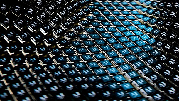 Digital art of a close up view of a blue and black pattern of little squares that all say AI.